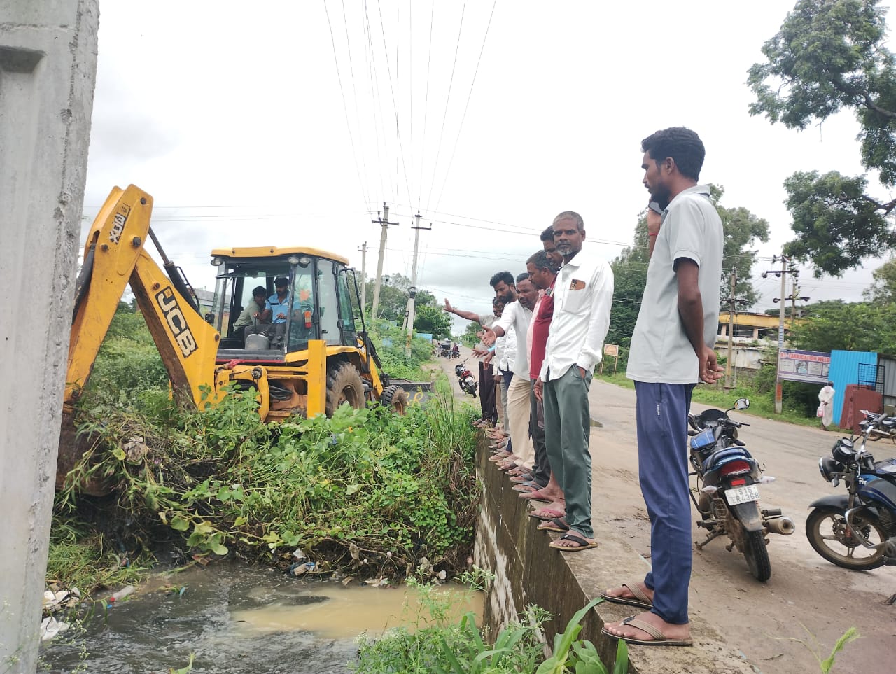 కట్టు కాలువలో పేరుకుపోయిన పిచ్చి మొక్కలు.సహాయక చర్యలు చేపట్టిన హత్నూర గ్రామస్తులు.